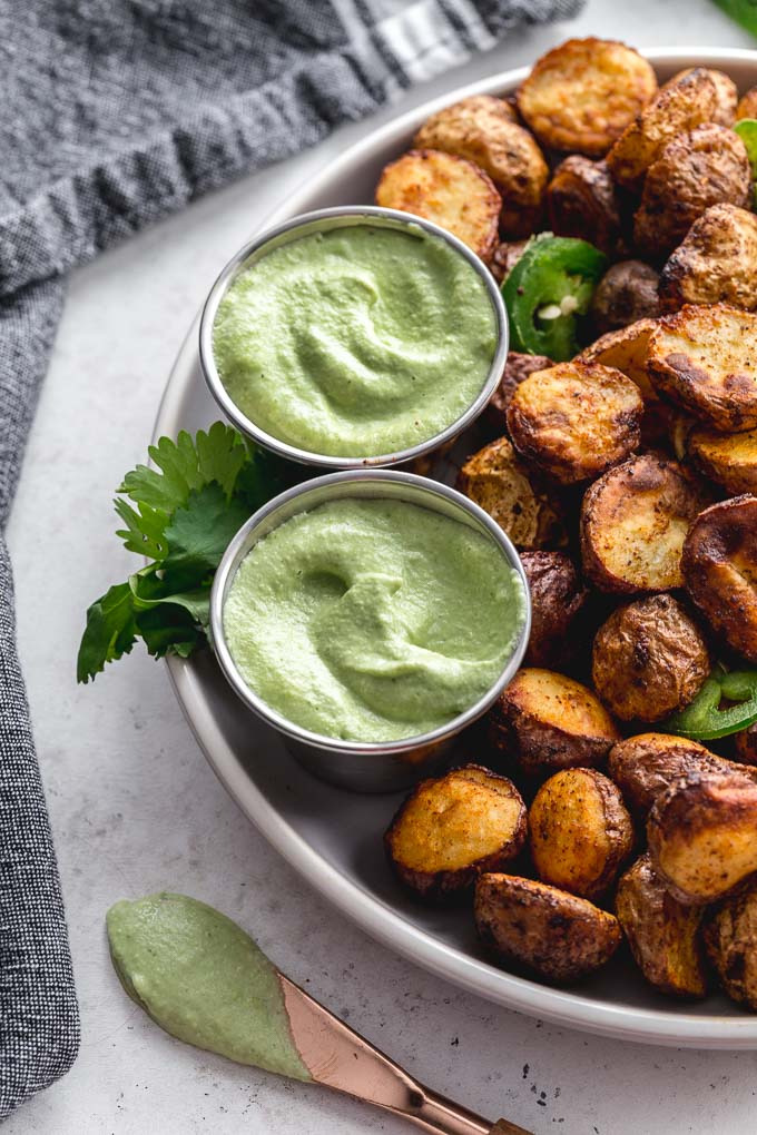 Vegan jalapeño dip in serving cups with a plate of home fries.