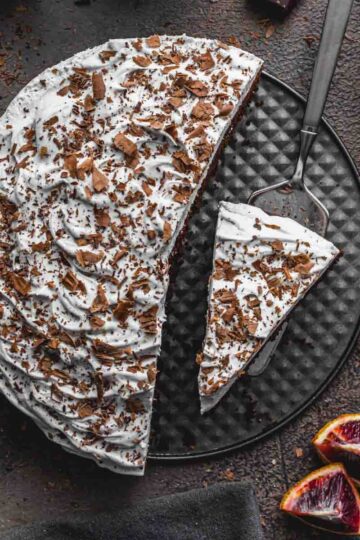 Overhead of blood orange chocolate cake with slices being removed.