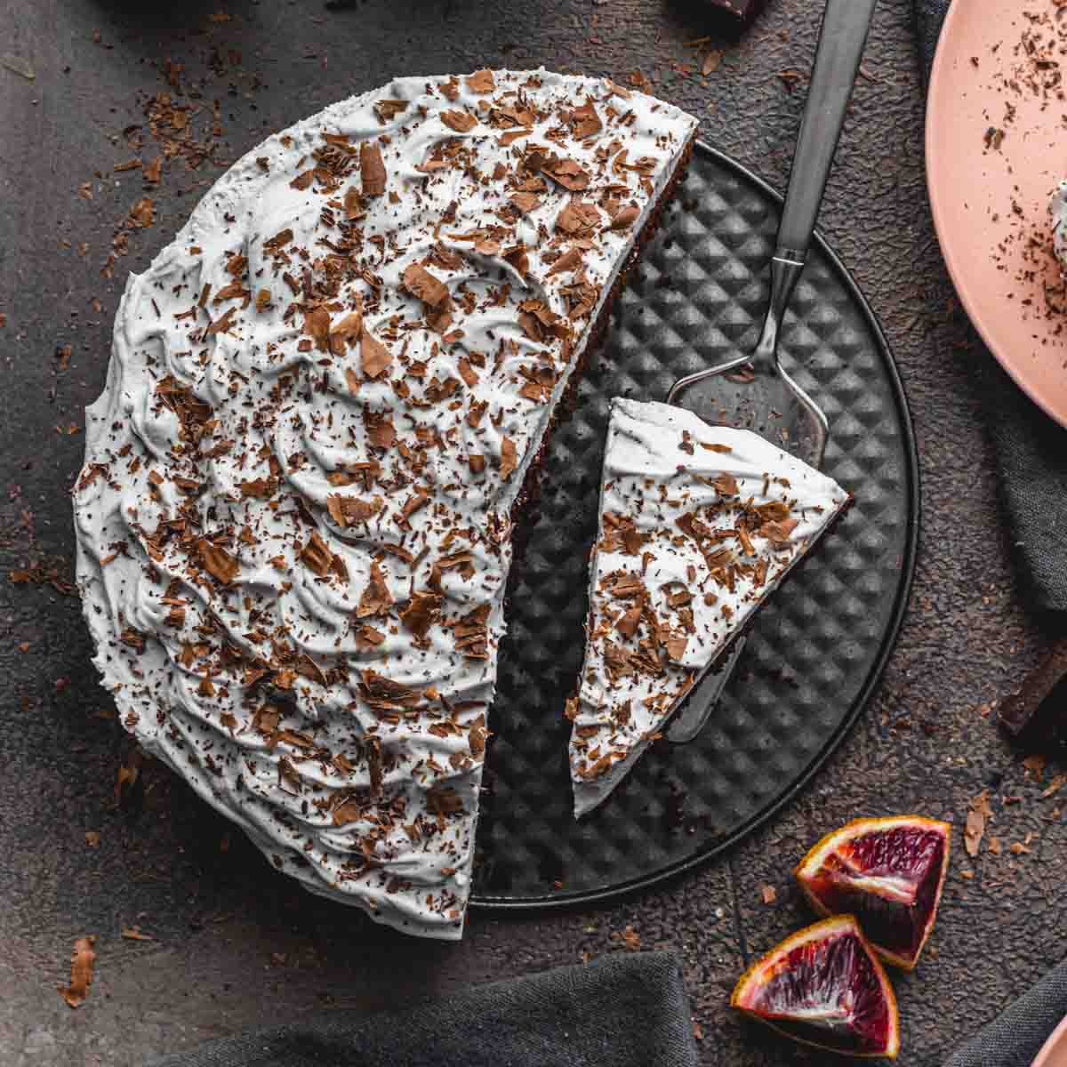 Overhead of blood orange chocolate cake with slices being removed.