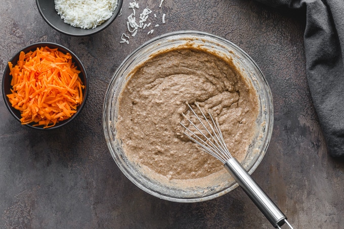 Batter for dairy-free carrot cake being whisked together in a glass bowl.