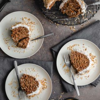 Overhead view of pieces of coconut carrot cake served on white plates.