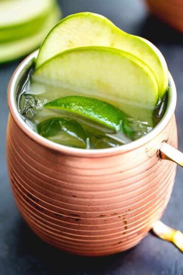 Green apple Irish mule with apple slices and lime wedge on top.