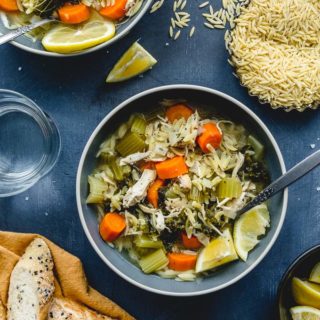 Instant Pot Chicken Orzo Soup served up in blue bowls and garnished with lemon slices.