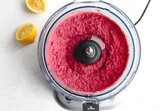 Overhead view of white bean beet hummus blended together in a food processor.