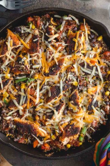 Overhead of salmon quinoa bake in a cast iron skillet with a wooden spoon on the side.