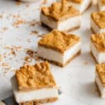Angled view of carrot cake ice cream sandwiches cut into squares and arranged on parchment paper.