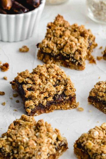 Healthy date squares arranged on parchment paper with dates and oats in the background.