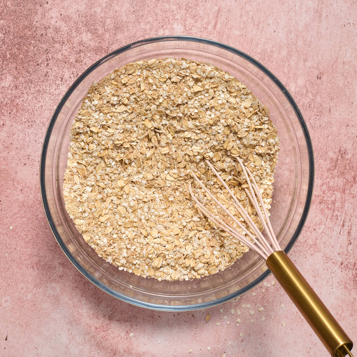 Dry oat and quinoa mixture whisked together in a glass bowl.