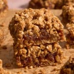 Two date squares stacked together on brown parchment paper.