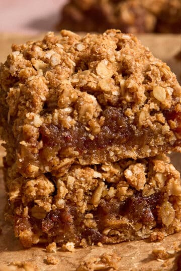 Two date squares stacked together on brown parchment paper.