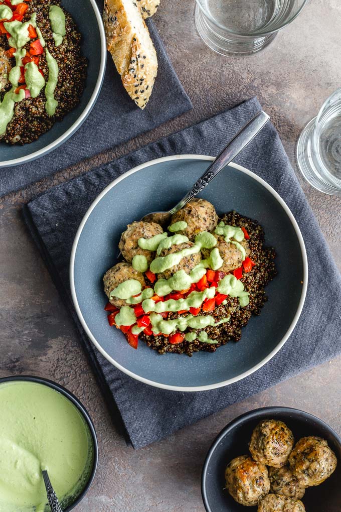 Overhead view of a meatball quinoa bowl with jalapeno sauce drizzled on top.