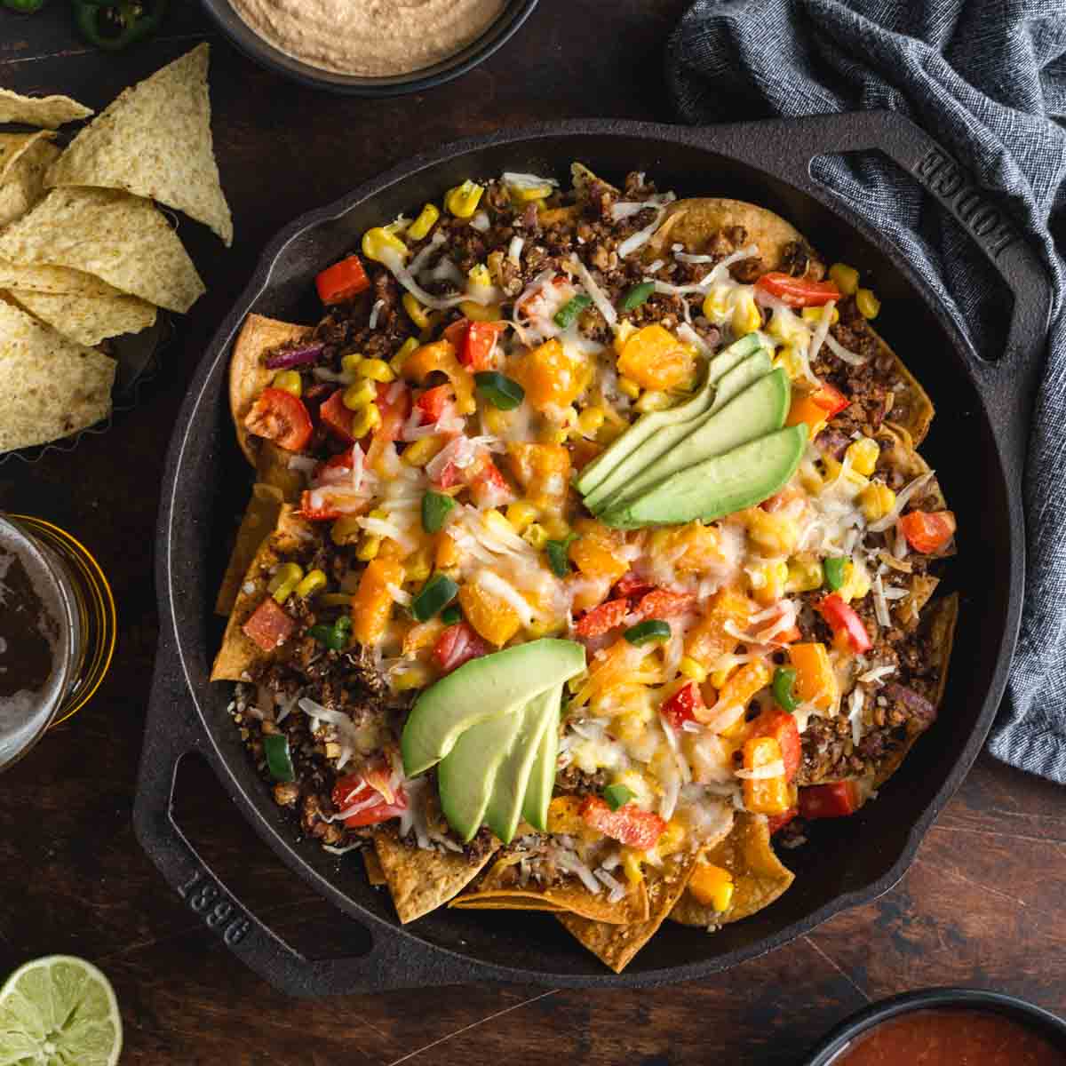 Overhead of loaded veggie nachos in a black cast iron skillet.