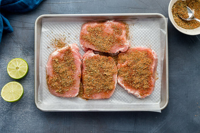Raw pork chops coated in seasonings.