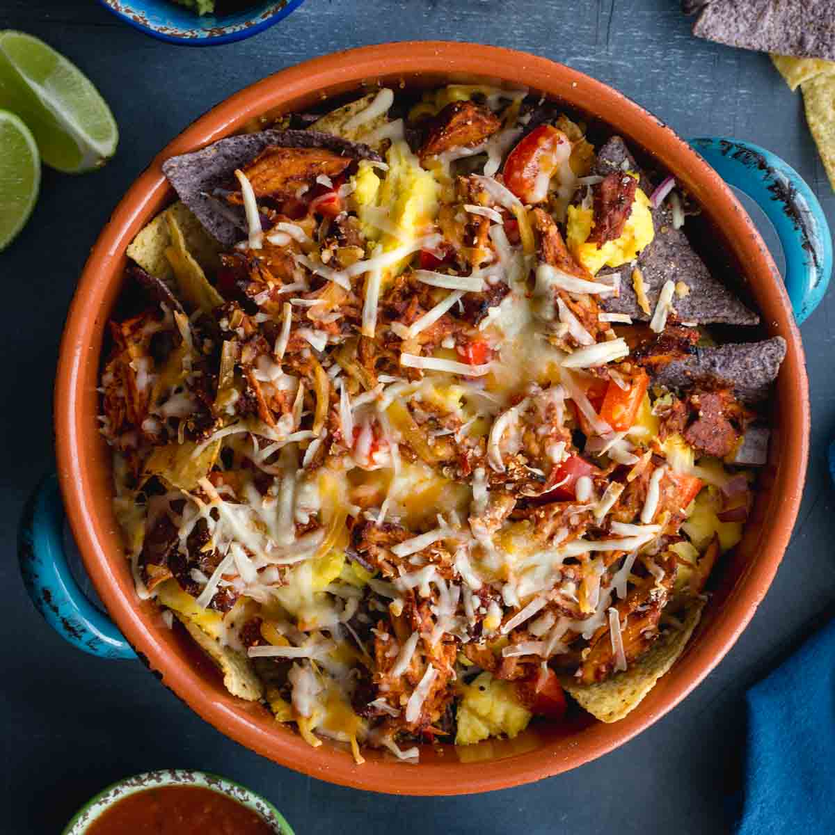 Overhead of pulled pork breakfast nachos in a round casserole dish.