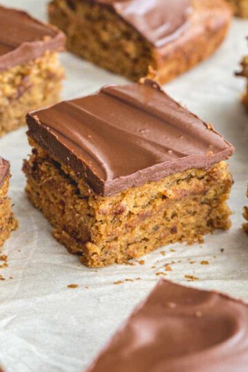 Angled view of square pieces of banana snack cake arranged on white parchment paper.