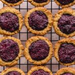 Overhead close up of peanut butter and jam cookie cups on a wire rack.
