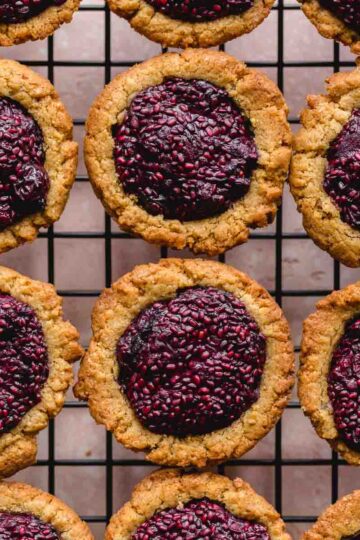 Overhead close up of peanut butter and jam cookie cups on a wire rack.