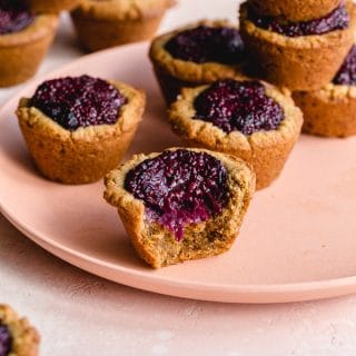 Peanut butter and jam cookies arranged on a pink plate.