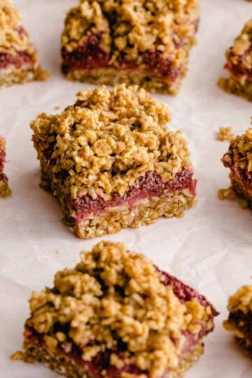Strawberry oat bars cut into squares and arranged on white parchment paper.