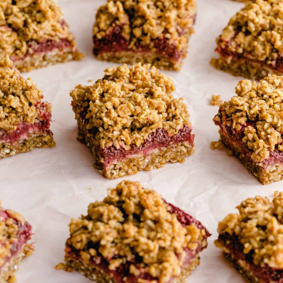 Strawberry oat bars cut into squares and arranged on white parchment paper.