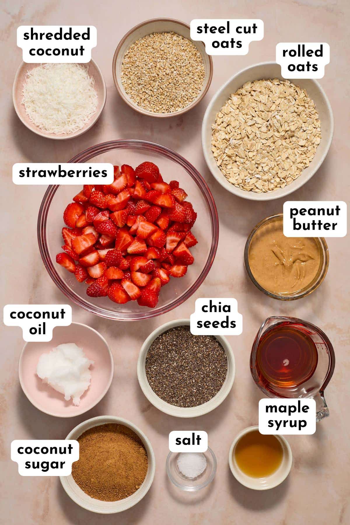 Ingredients to make strawberry oat bars arranged in individual dishes and labeled.