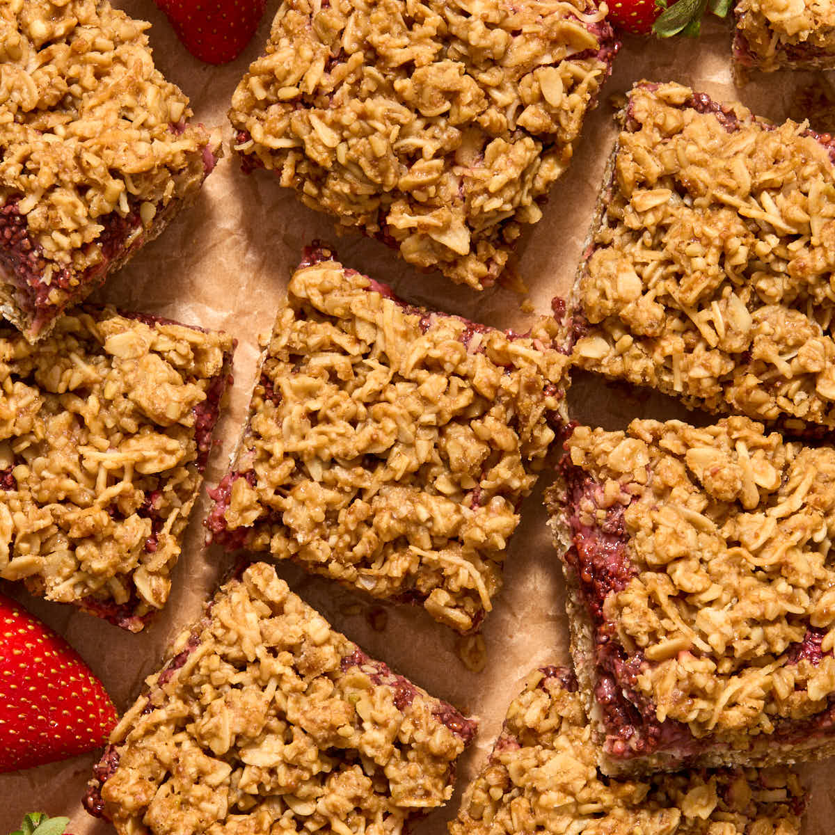 Strawberry bars arranged close together on parchment paper.