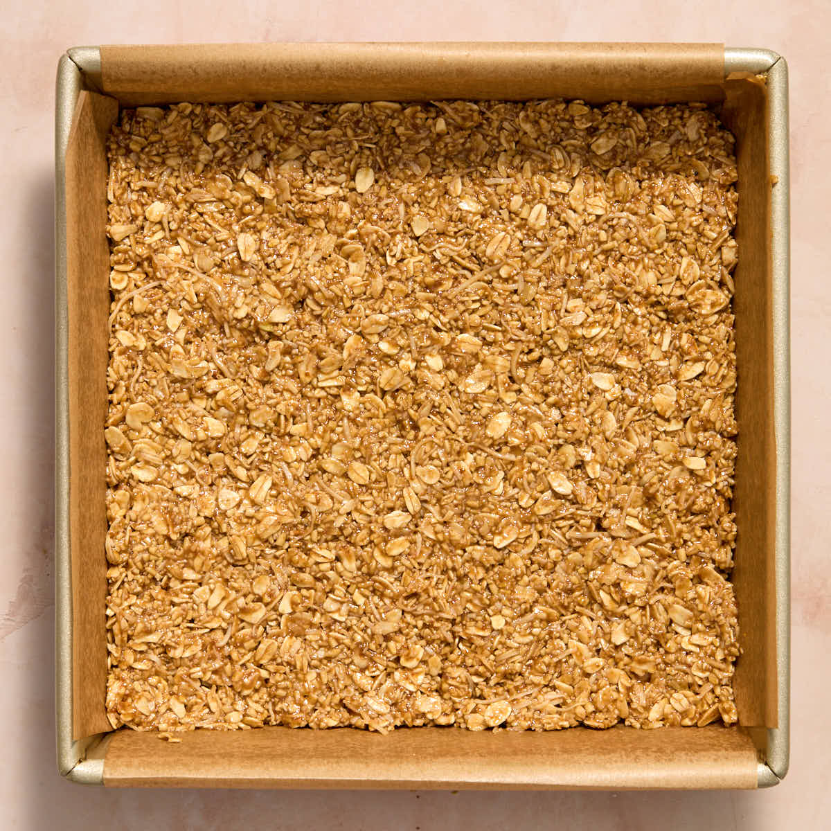 Some of the oat mixture pressed into the bottom of a square pan.