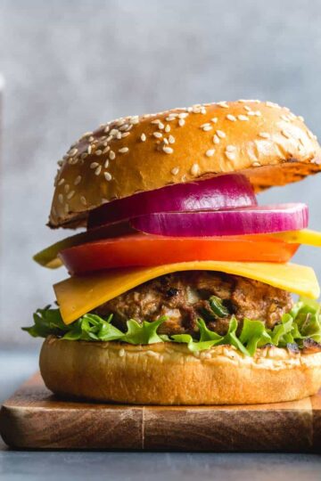 Side view of a turkey jalapeno burger topped with lettuce, cheese, tomato and red onion.