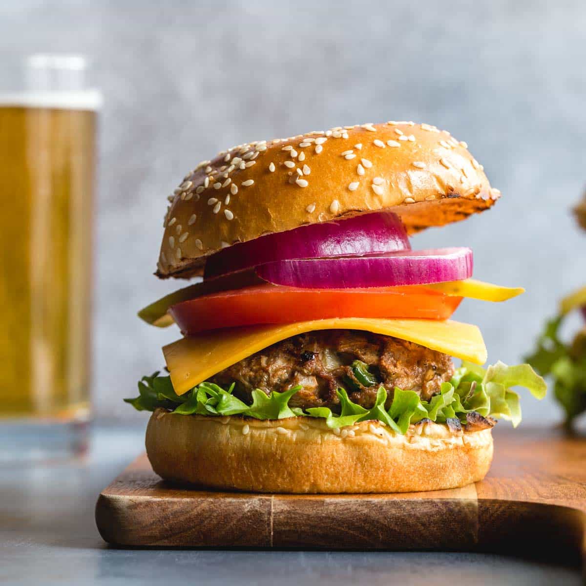 Side view of a turkey jalapeno burger topped with lettuce, cheese, tomato and red onion.