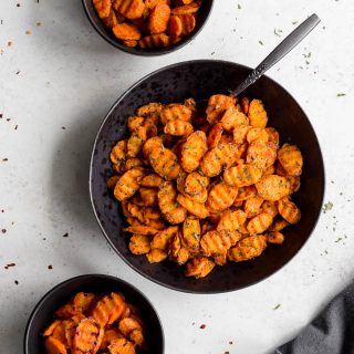 Three bowls of air fryer carrots arranged on a white surface.