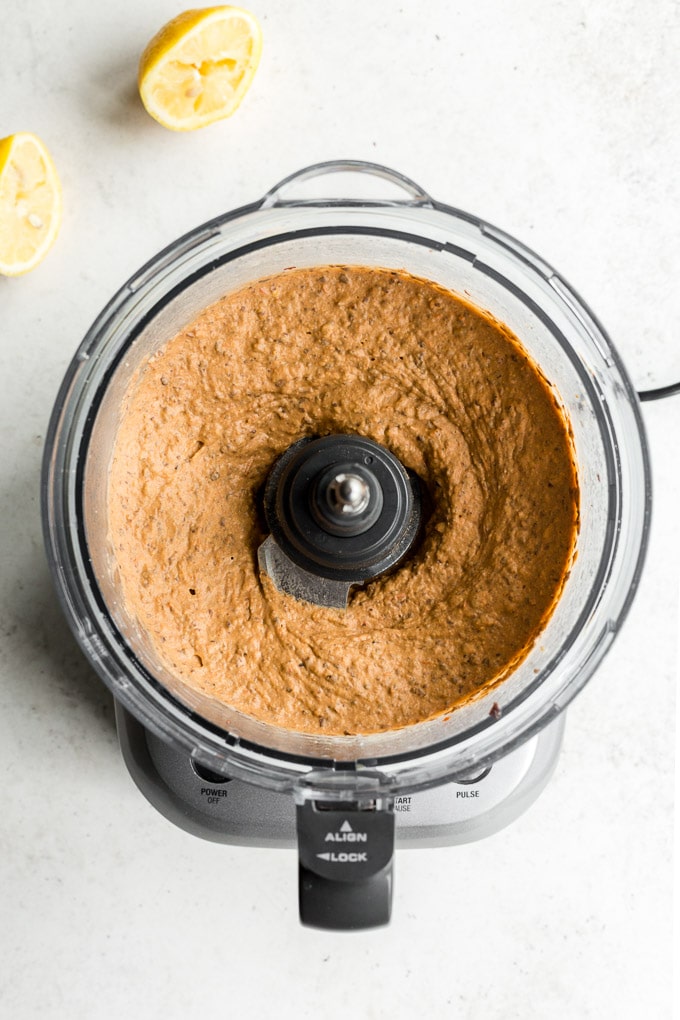 Roasted red pepper and black bean hummus mixed together in a food processor bowl.