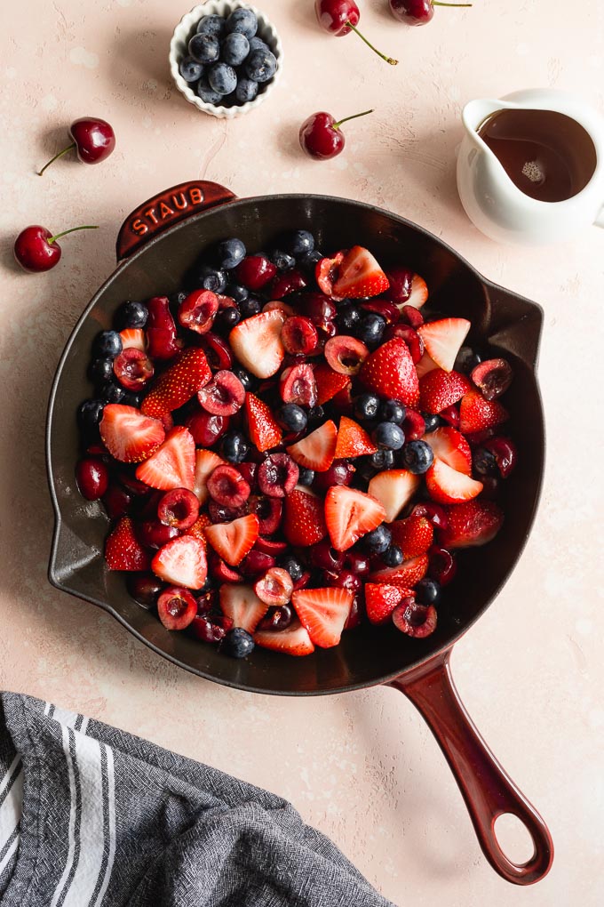 Cherries, strawberries and blueberries in a cast iron skillet.