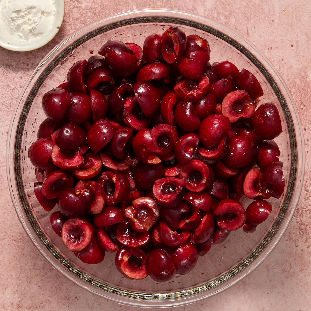 Cherries in a large glass bowl with cornstarch on the side.