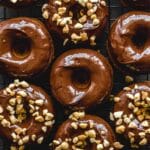 Overhead close up of peanut butter banana protein donuts topped with chocolate and crushed peanuts.