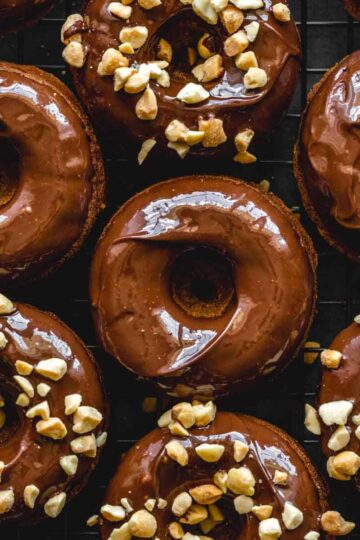 Overhead close up of peanut butter banana protein donuts topped with chocolate and crushed peanuts.