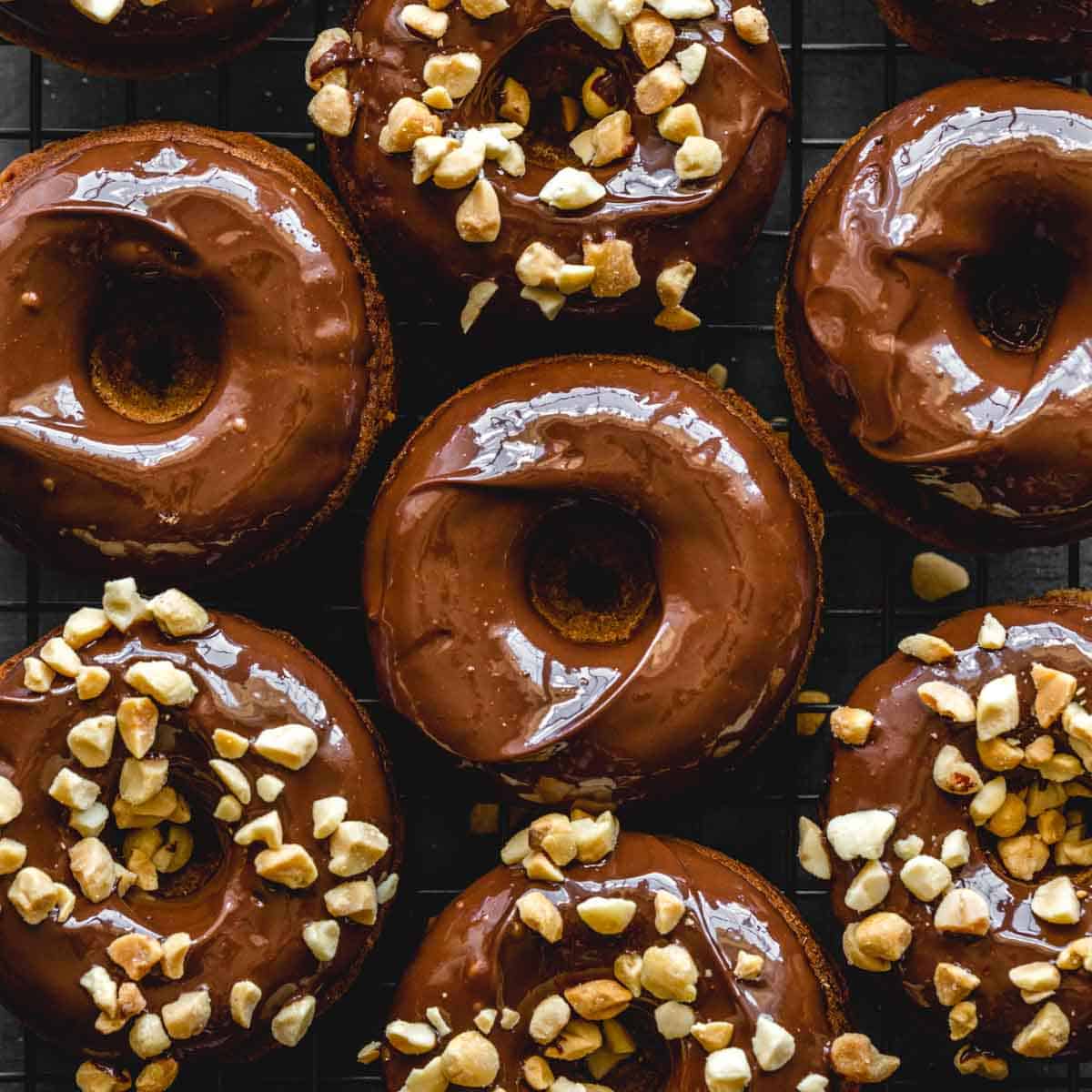 Overhead close up of peanut butter banana protein donuts topped with chocolate and crushed peanuts.