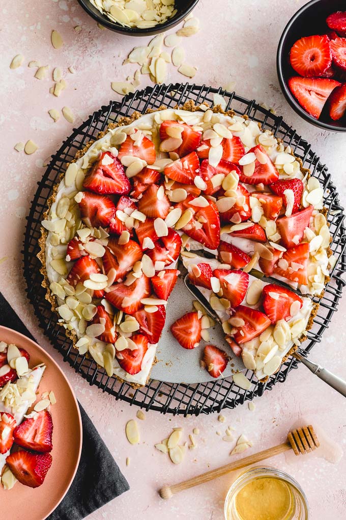 Overhead view of strawberry custard tart with pieces cut out.