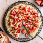 Overhead of vegan strawberry custard tart with slices being cut out.