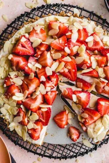 Overhead of vegan strawberry custard tart with slices being cut out.