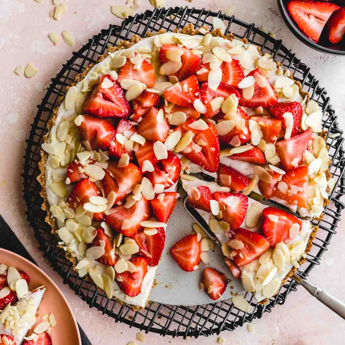 Overhead of vegan strawberry custard tart with slices being cut out.