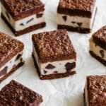 Brownie ice cream sandwiches cut into squares and arranged on white parchment paper.