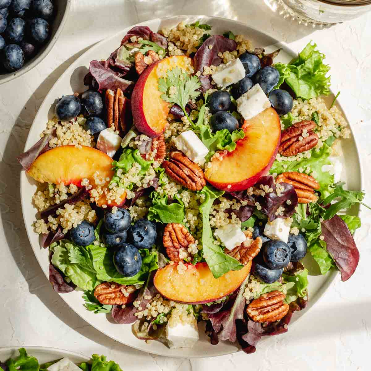 Overhead of blueberry peach summer salad on a white plate.