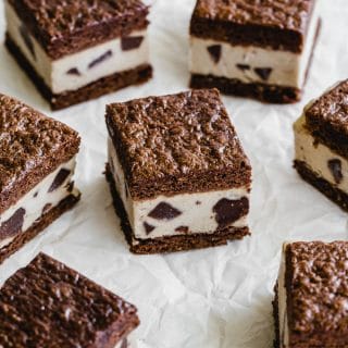 Brownie ice cream sandwiches arranged on a crumpled sheet sheet of parchment paper.