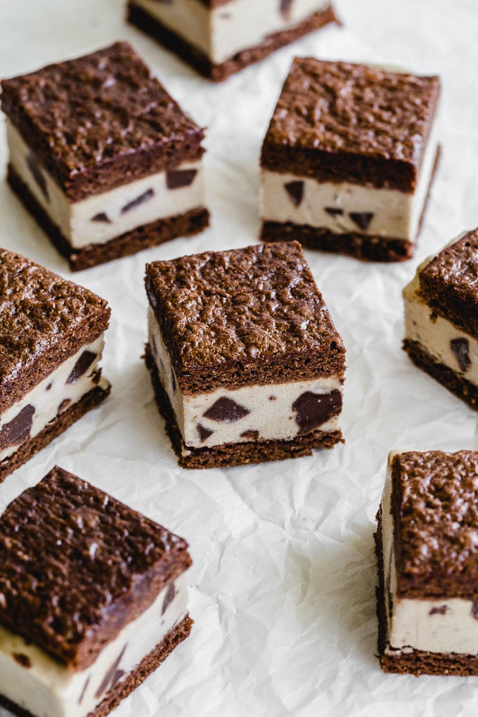 Peanut butter brownie ice cream sandwiches arranged on a sheet of parchment paper.