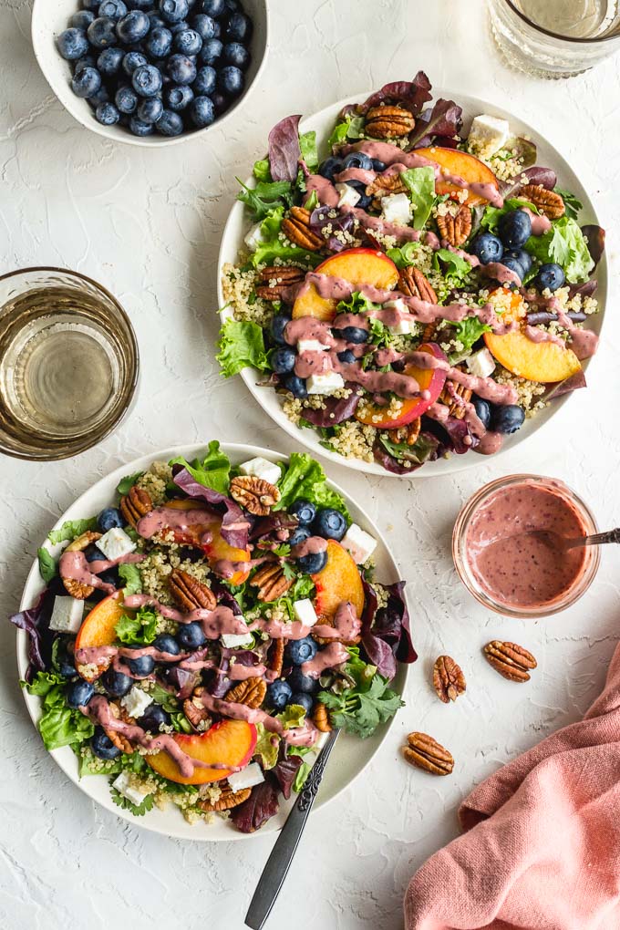 Summer peach salad with blueberries arranged on white plates and topped with blueberry peach balsamic dressing.