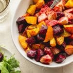 Up close view of air fryer roasted beets in a white bowl with a spoon inserted into the beets.