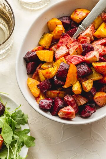 Up close view of air fryer roasted beets in a white bowl with a spoon inserted into the beets.