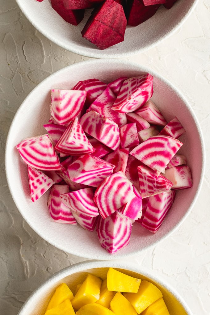Up close view of candy cane beets cut into cubes and sitting in a white bowl.