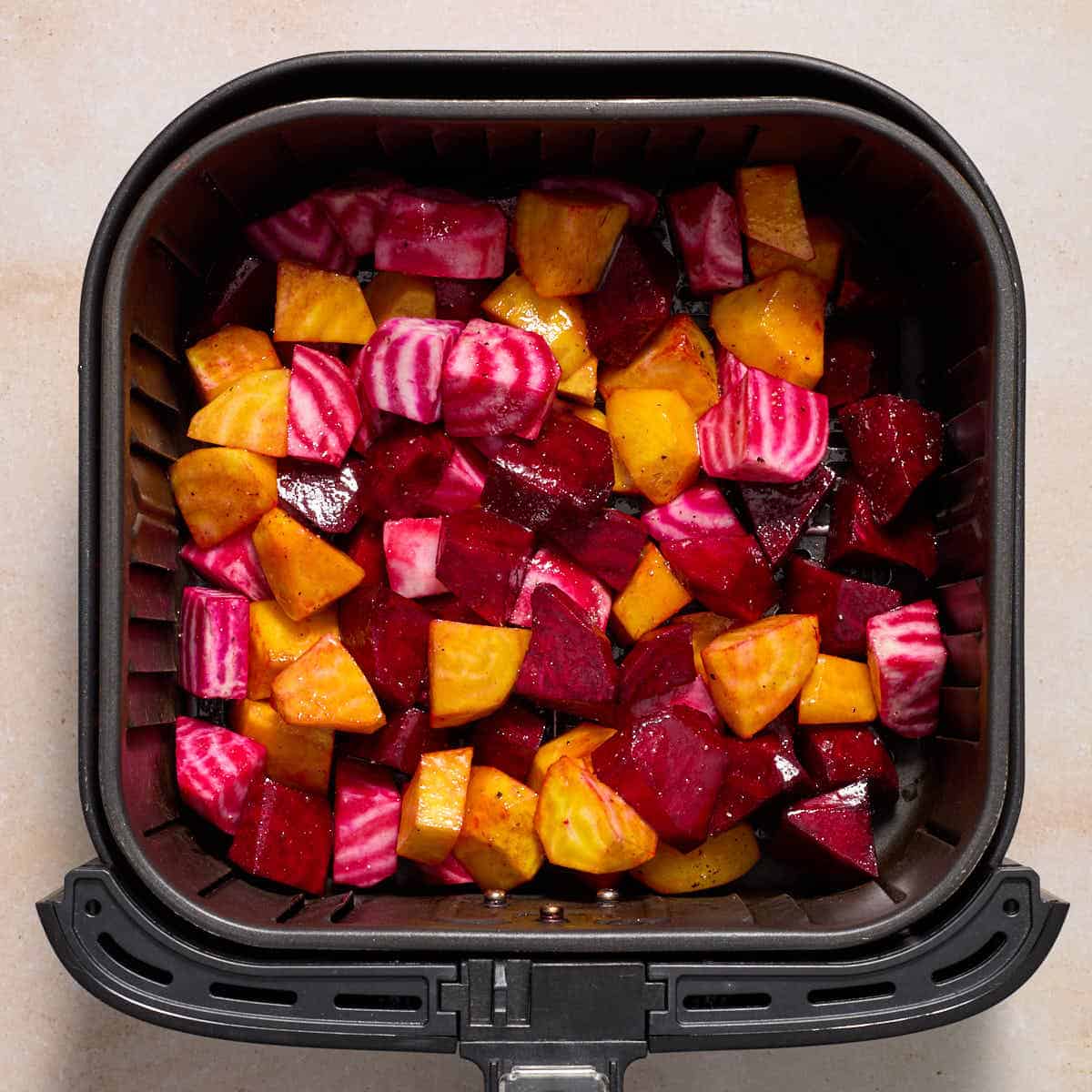 Raw, seasoned beets in an air fryer basket.