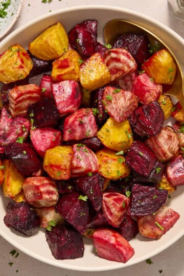Air fryer beets served in a white bowl with a serving spoon in the bowl.